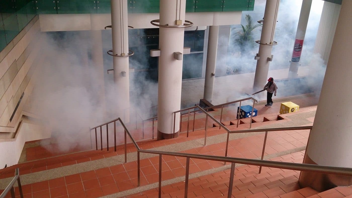 Pest control technician fogging an indoor commercial stairwell